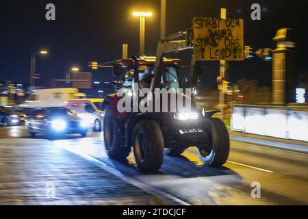 Leipzig, Allemagne. 18 décembre 2023. L'un des nombreux agriculteurs conduit dans la circulation des heures de pointe tôt le matin avec son tracteur et une affiche de protestation. Les agriculteurs veulent se mobiliser lundi à Berlin pour protester contre la suppression prévue des allégements fiscaux par la coalition des feux de circulation. Sous le slogan "trop c'est trop", un rassemblement est prévu à la porte de Brandebourg dans la matinée. Crédit : Jan Woitas/dpa/Alamy Live News Banque D'Images