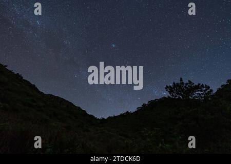 Ciel nocturne plein d'étoiles et queue de voie lactée du sommet de Doi Luang Chiang Dao à Chiang Mai, Thaïlande avec silhouette de montagnes au sommet dans le for Banque D'Images