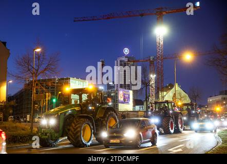 Leipzig, Allemagne. 18 décembre 2023. Plusieurs agriculteurs conduisent leurs tracteurs dans la circulation aux heures de pointe tôt le matin. Les agriculteurs veulent se mobiliser lundi à Berlin pour protester contre la suppression prévue des allégements fiscaux par la coalition des feux de circulation. Sous le slogan "trop c'est trop", un rassemblement est prévu à la porte de Brandebourg dans la matinée. Crédit : Jan Woitas/dpa/Alamy Live News Banque D'Images