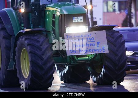 Leipzig, Allemagne. 18 décembre 2023. L'un des nombreux agriculteurs conduit dans la circulation des heures de pointe tôt le matin avec son tracteur et une affiche de protestation. Les agriculteurs veulent se mobiliser lundi à Berlin pour protester contre la suppression prévue des allégements fiscaux par la coalition des feux de circulation. Sous le slogan "trop c'est trop", un rassemblement est prévu à la porte de Brandebourg dans la matinée. Crédit : Jan Woitas/dpa/Alamy Live News Banque D'Images