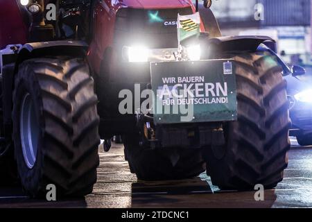 Leipzig, Allemagne. 18 décembre 2023. L'un des nombreux agriculteurs conduit dans la circulation des heures de pointe tôt le matin avec son tracteur et une affiche de protestation. Les agriculteurs veulent se mobiliser lundi à Berlin pour protester contre la suppression prévue des allégements fiscaux par la coalition des feux de circulation. Sous le slogan "trop c'est trop", un rassemblement est prévu à la porte de Brandebourg dans la matinée. Crédit : Jan Woitas/dpa/Alamy Live News Banque D'Images