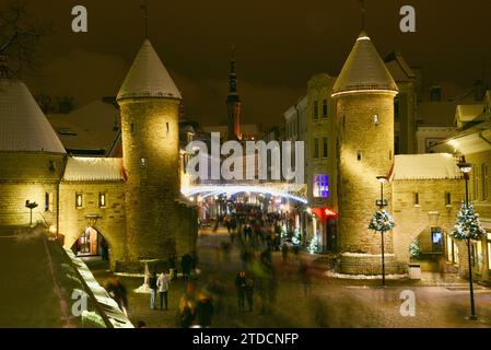 Tours en pierre de la porte Viru avec des centaines de clients et des foules festives marchant (motion blur) vers le marché de Noël dans la vieille ville de Tallinn, Estonie Banque D'Images