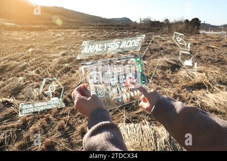 Dans les rizières d'hiver récoltées, une femme utilise un dispositif AR pour analyser le sol et le progrès (hologramme et effets CG sont appliqués) Banque D'Images