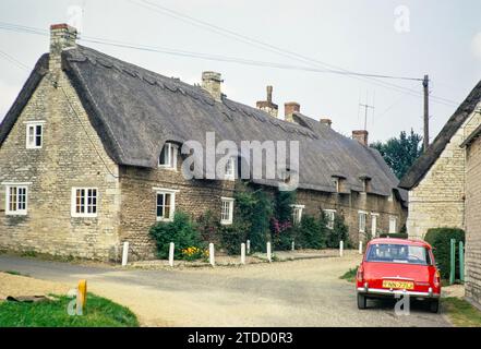 Chaumières à Crocket Lane, village d'Empingham, Rutland, Angleterre, Royaume-Uni août 1972 Red Austin Morris 1100 Mk 2 voiture Banque D'Images