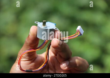 Moteur pas à pas qui fonctionne sur une alimentation cc isolé sur fond de nature tenu en main Banque D'Images