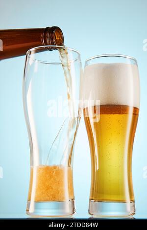 Lager, ALE coule pour vider les grands verres de la bouteille. Banque D'Images