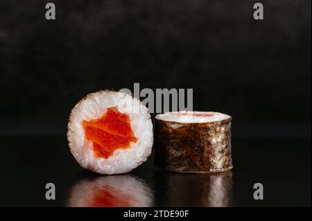 Les sushis japonais roulent sur un fond sombre avec réflexion Banque D'Images