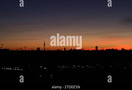 München, Deutschland 17. Décembre 2023 : hier der Blick von der Esplanade, Allianz Arena auf die Skyline von München BEI Dämmerung, Abend, Sonnenuntergang, In der Mitte kann man den Olympiaturm, Fernsehturm erkennen, Färbung, Farbenspiel, Munich, Häuser *** Munich, Allemagne 17 décembre 2023 Voici la vue de l'Esplanade, Allianz Arena sur la Skyline de Munich au crépuscule, soir, coucher de soleil, au milieu vous pouvez voir la Tour Olympique, Tour de télévision, coloriage, jeu de couleurs, Munich, maisons Banque D'Images