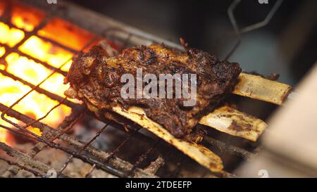 Gros plan du processus de grillade sur une grande taille de côtes de bœuf sur feu de charbon traditionnel. Plat indonésien appétissant. Vidéo sur la nourriture. Banque D'Images