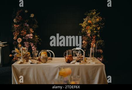 Réglage de table élégant, propre et facile pour fête intérieure, réception de mariage avec luxe, grande décoration de fleur sur le mur. Table d'événement spécial mise en place avec Banque D'Images