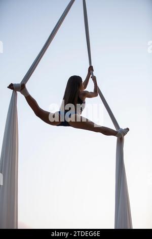 Jeune femme jouant sur la soie aérienne en plein air Banque D'Images