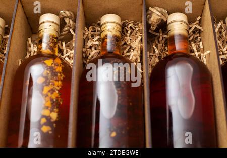 Bouteilles avec brandy de boisson alcoolisée maison chère et cognac dans une boîte en bois, gros plan. Banque D'Images