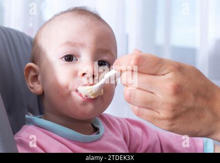 Une mère nourrit son enfant, un garçon d'un an, avec de la bouillie de millet. Nourrir les enfants sans lait et sans gluten porridge avec des vitamines et des macroelemen Banque D'Images