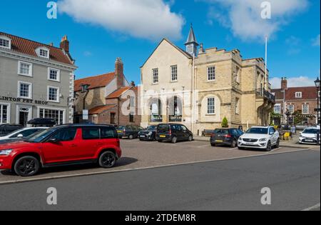 L'ancien hôtel de ville et les voitures garées dans la rue Market place en été Malton North Yorkshire Angleterre Royaume-Uni GB Grande-Bretagne Banque D'Images