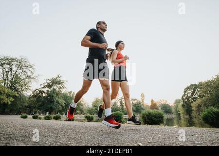 Couple actif courant ensemble dans le parc, profitant d'une séance d'entraînement l'après-midi. Banque D'Images