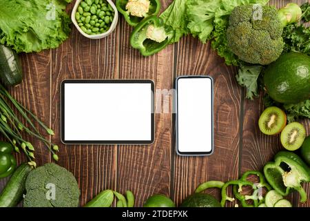 Smartphone et tablette sur table en bois avec épicerie fraîche, vue de dessus Banque D'Images