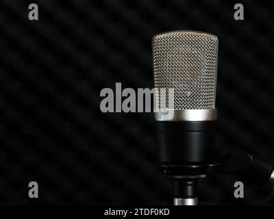 Microphone à condensateur avec un grand diaphragme sur un fond sombre de la surface insonorisée du mur du studio Banque D'Images