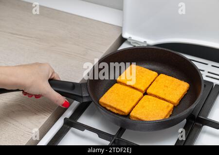 femme faisant frire des côtelettes de poisson panées dans une poêle. faire de grosses pépites à la maison. côtelette panée Banque D'Images