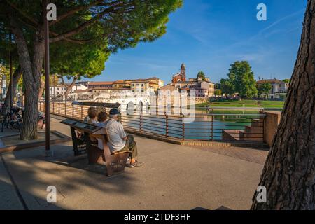 Habitants regardant Ponte di Tiberio reflétant dans le Canal de Rimini de Borgo San Giuliano, Rimini, Emilie-Romagne, Italie, Europe Banque D'Images