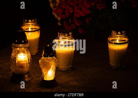 Cliché de nuit des flammes des bougies de cimetière en verre debout sur les pierres tombales. Le tir a été pris pendant la Toussaint, le 1 novembre. Banque D'Images