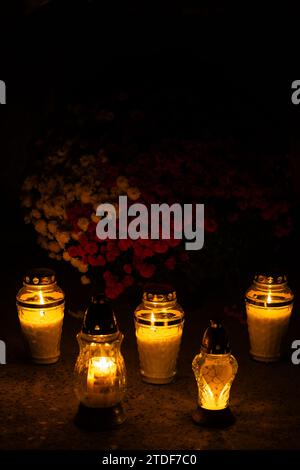 Cliché de nuit des flammes des bougies de cimetière en verre debout sur les pierres tombales. Le tir a été pris pendant la Toussaint, le 1 novembre. Banque D'Images