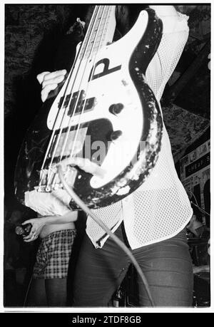 KATHLEEN HANNA, BIKINI KILL, NEWPORT TJS, 1993 : Kathleen Hanna la chanteuse de bikini Kill cache le groupe de la caméra avec sa guitare basse au légendaire TJS à Newport, pays de Galles, Royaume-Uni le 8 mars 1993. Ce bikini Kill/Huggy Bear Tour est arrivé au sommet de la scène Riot Grrrl et était de promouvoir l'album Yeah Yeah Yeah Yeah Yeah (Kill Rock Stars) des deux groupes combinés en 1993. Le concert a commencé par un atelier de musique pour les femmes seulement. Photo : Rob Watkins Banque D'Images