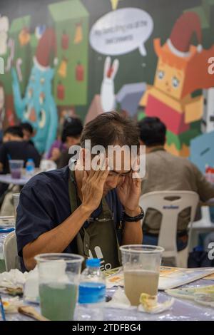 Bangkok, Thaïlande. 08 décembre 2023. Un homme est vu tenant sa tête pendant le concours de peinture à l'aquarelle "BEM Art Contest", à la station MRT Phahon Yothin. Le « Metro Art » au MRT Phahon Yothin, développé par Bangkok Expressway and Metro public (BEM), Bangkok Metro Networks Limited (BMN), et soutenu par l'Autorité du tourisme de Thaïlande (TAT) est le nouvel espace d'art et destination d'art au cœur de la ville comme la station MRT Phahon Yothin se connecte à tous les quartiers de Bangkok, où les visiteurs peuvent apprendre les arts dans divers domaines, magasiner et vendre des œuvres d'art. Crédit : SOPA Images Limited/Alamy Live News Banque D'Images