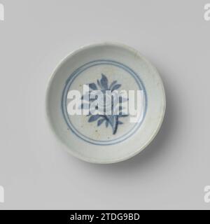 Soucoupe-plat avec un spray de fleurs dans un médaillon, anonyme, c. 1300 - c. 1499 échelle de porcelaine, peinte en bleu sous-glacé. Sur le plat une branche de fleur stylisée dans un double médaillon. Le glaçage est rampant ; le dessous n'est pas vitré. Trouvé sur Sulawesi. Bleu blanc. Porcelaine de Chine. glaçage. Cobalt (minéral) peinture / vitrification échelle de porcelaine, peinte en bleu sous glaçure. Sur le plat une branche de fleur stylisée dans un double médaillon. Le glaçage est rampant ; le dessous n'est pas vitré. Trouvé sur Sulawesi. Bleu blanc. Porcelaine de Chine. glaçage. cobalt (minéral) peinture / vitrification Banque D'Images