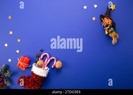 Tradition du jour de l'Epiphanie. Befana et bas rouge avec charbon doux et bonbons sur fond bleu foncé. Banque D'Images