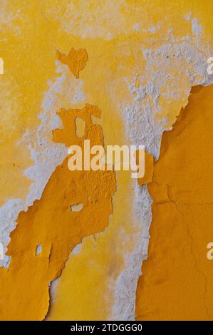 Abstrait, détail, motif coloré de couches de peinture écaillées multicolores, jaunes, ocres et orange sur un vieux mur extérieur en pierre d'un bâtiment à Jeru Banque D'Images