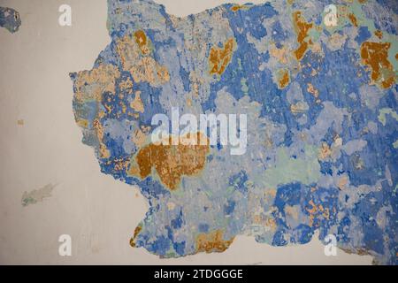 Motif abstrait, détaillé, coloré et texturé de couches de peinture bleu, vert et orange pelées multicolores sur un vieux mur extérieur en pierre d'un bâtiment Banque D'Images