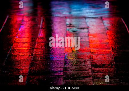 Rendu abstrait du pavement lisse de Jaffa Road dans le centre-ville de Jérusalem illuminé par une lumière artificielle lumineuse et colorée par une nuit d'hiver pluvieuse Banque D'Images