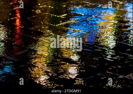 Rendu abstrait du pavement lisse de Jaffa Road dans le centre-ville de Jérusalem illuminé par une lumière artificielle lumineuse et colorée par une nuit d'hiver pluvieuse Banque D'Images