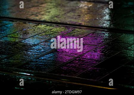 Rendu abstrait du pavement lisse de Jaffa Road dans le centre-ville de Jérusalem illuminé par une lumière artificielle lumineuse et colorée par une nuit d'hiver pluvieuse Banque D'Images