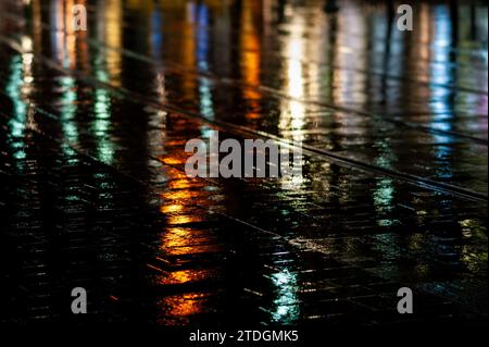 Rendu abstrait du pavement lisse de Jaffa Road dans le centre-ville de Jérusalem illuminé par une lumière artificielle lumineuse et colorée par une nuit d'hiver pluvieuse Banque D'Images