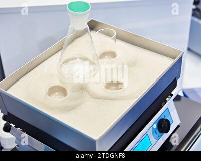 Plaque chauffante de laboratoire avec tubes à essai et fioles dans bain de sable Banque D'Images