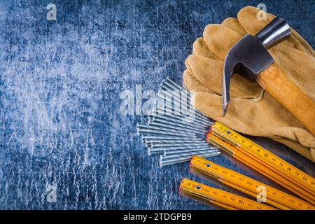 Copier l'image de l'espace des gants de travail en cuir clous compteur de mesure en bois et marteau à griffes sur le concept de construction de fond métallique rayé Banque D'Images