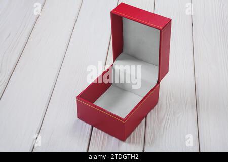 Boîte cadeau vide, ouverte et recouverte de cuir rouge sur une table en bois blanc Banque D'Images