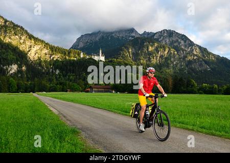 Cycliste devant le château de Neuschwanstein, Hohenschwangau, haute-Bavière, Bavière, Allemagne Banque D'Images