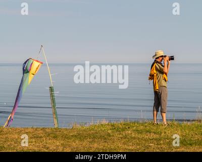 Un homme (moi-même) photographie le paysage devant le fleuve Saint-Laurent en face du Mont-St-Pierre au lever du jour. Mont-Saint-Pierre, Québec, Canada. Banque D'Images