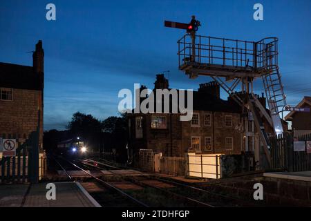 Train Turbostar de classe 170 du rail du Nord arrivant à la gare de Knaresborough au crépuscule, avec la boîte de signalisation et le signal de support de sémaphore Banque D'Images