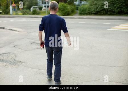 L'homme part sur la route. L'homme traverse la transition. Guy dans la rue. Promenade autour de la ville. Banque D'Images