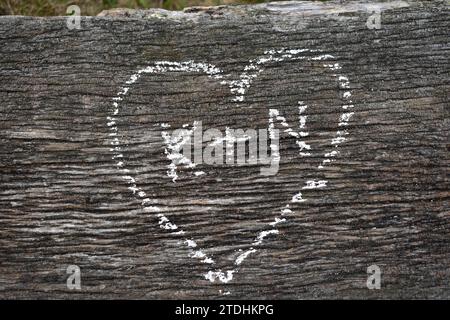 K + N écrit à l'intérieur d'un coeur, dessiné à la craie blanche sur une surface en bois altérée Banque D'Images