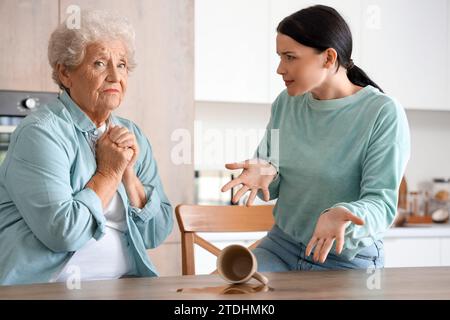Femme aînée et sa fille bouleversées par le thé renversé dans la cuisine Banque D'Images