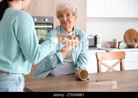 Femme aînée et sa fille bouleversées par le thé renversé dans la cuisine Banque D'Images