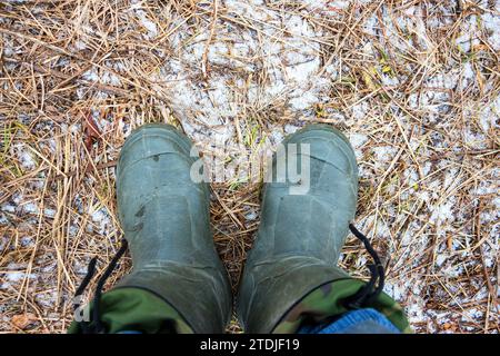 Pieds en bottes sur le sol gelé. Vue d'en haut Banque D'Images