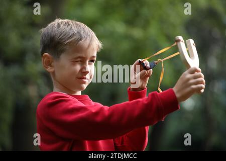 Petit garçon jouant avec la fronde dans le parc Banque D'Images