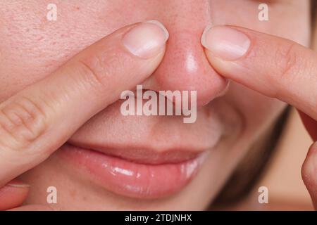 Femme qui fait sauter le bouton sur son nez, gros plan Banque D'Images