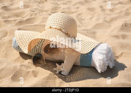 Chapeau de paille, serviette, crème solaire, étoiles de mer et lunettes de soleil sur sable Banque D'Images