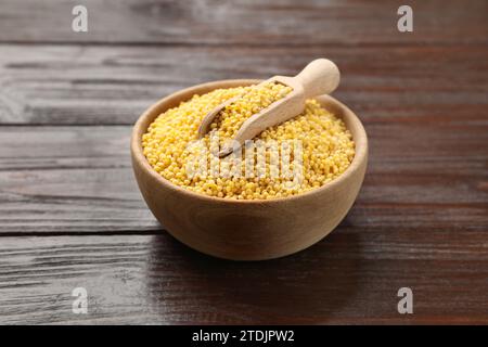 Gruaux de millet dans un bol et pelle sur une table en bois Banque D'Images